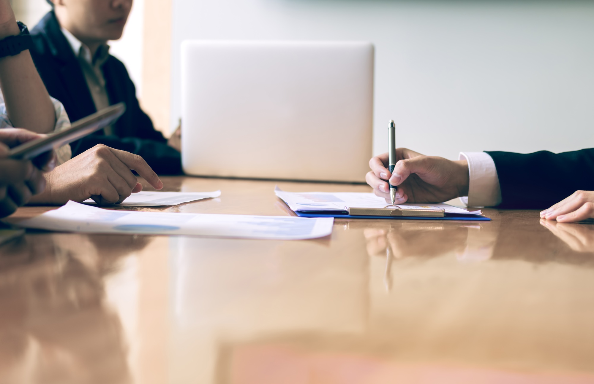 Boardroom with human resource business people writing paper negotiating a contract.